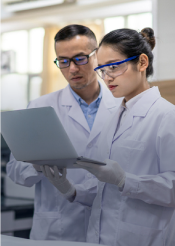 two lab technicians reviewing a laptop